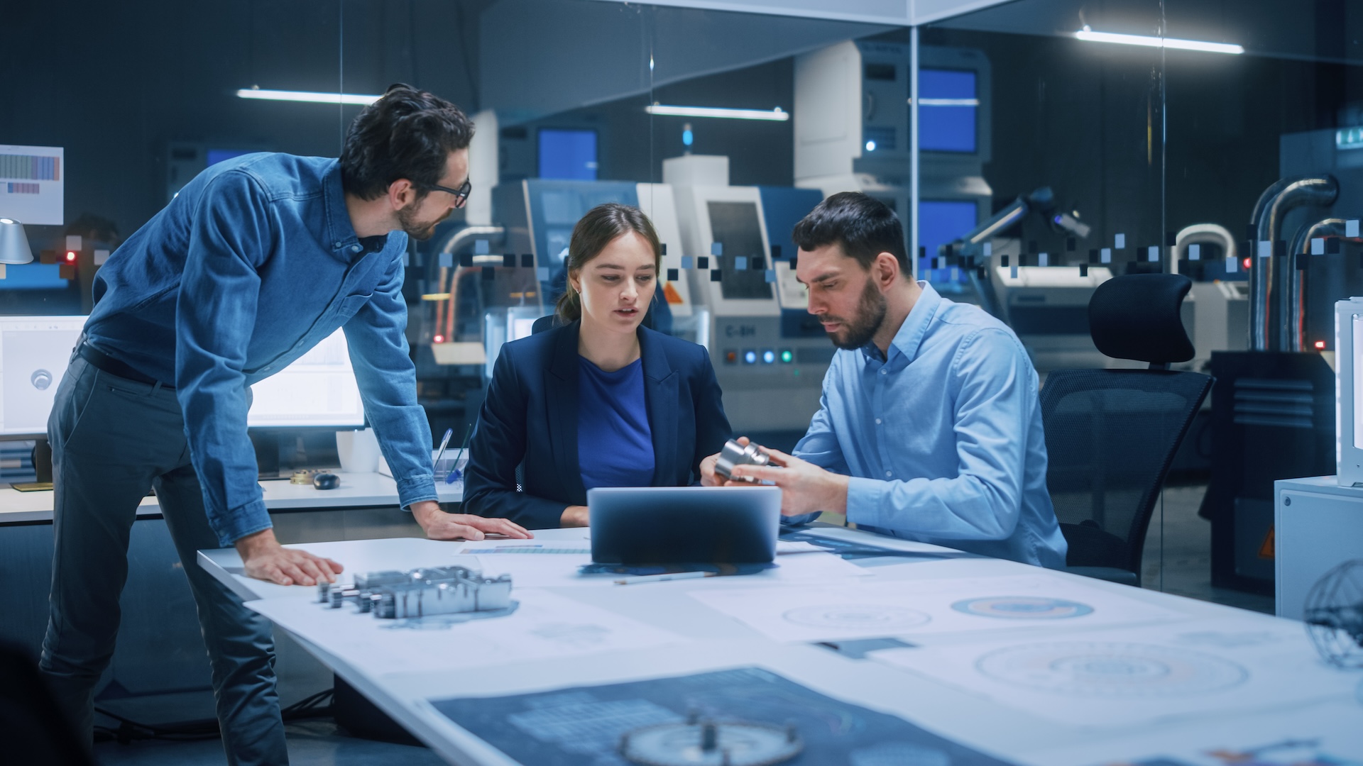 Factory Office Meeting Room: Team of Engineers Gather Around Conference Table, They Discuss Project Blueprints, Inspect Mechanism, Find Solutions, Use Laptop. Industrial Technology Factory